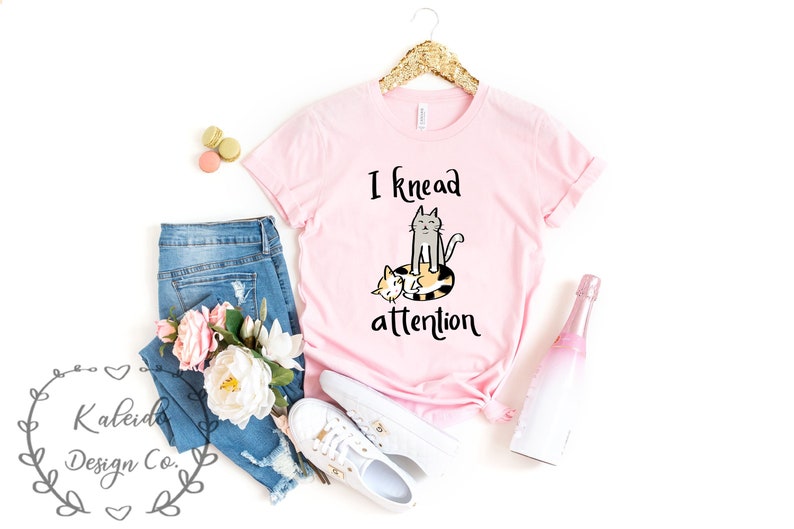 May include: Pink t-shirt with a graphic of two cats and the text "I knead attention".