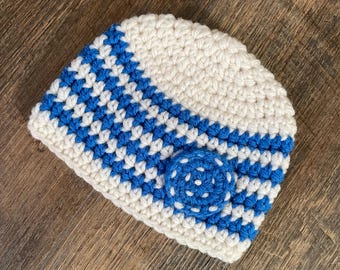 May include: A white and blue crocheted hat with a blue crocheted flower embellishment.