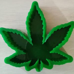 May include: Green leaf-shaped silicone mold for making resin crafts. The mold is shaped like a marijuana leaf with five points.