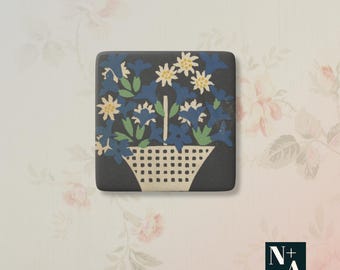 Könnte beinhalten: Quadratische, dunkelgraue dekorative Fliese mit floralem Design. Das Bild zeigt einen Korb mit blauen und weißen Blumen und grünen Blättern. Der Korb ist weiß mit einem Gittermuster. Der Hintergrund ist ein Blumenmuster.