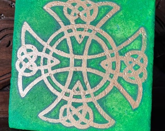 May include: A green square tile with a gold Celtic knot design. The knot is a traditional Irish symbol of eternity and interconnectedness.