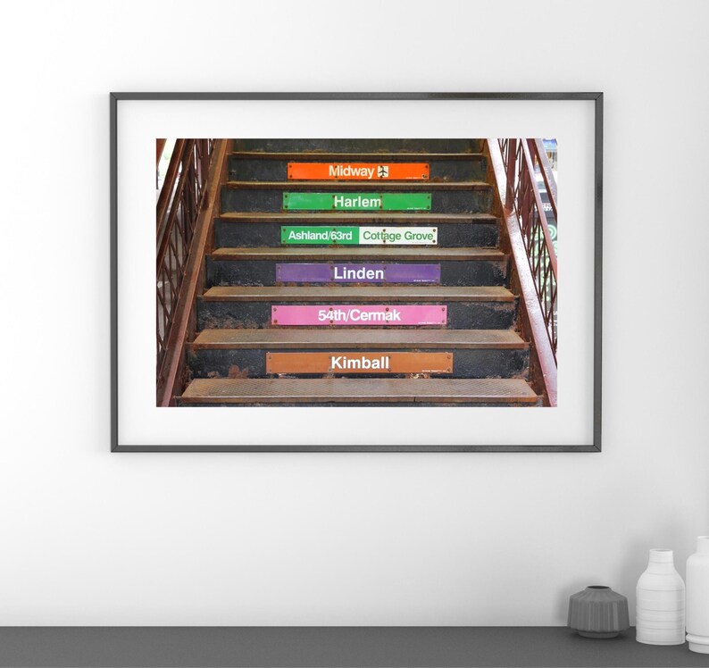 May include: A vintage-style subway station sign with the names of different Chicago train stops: Midway, Harlem, Ashland/63rd, Cottage Grove, Linden, 54th/Cermak, and Kimball.