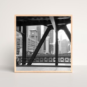 Puede incluir: Una fotograf&iacute;a en blanco y negro de un puente sobre un horizonte urbano. El puente est&aacute; hecho de acero y tiene un dise&ntilde;o de celos&iacute;a. El horizonte urbano est&aacute; en el fondo e incluye edificios altos con ventanas. La foto est&aacute; tomada desde el puente mirando hacia la ciudad.