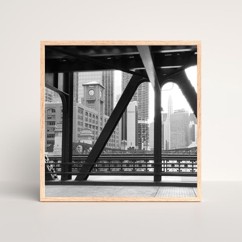 Puede incluir: Una fotograf&iacute;a en blanco y negro de un puente sobre un horizonte urbano. El puente est&aacute; hecho de acero y tiene un dise&ntilde;o de celos&iacute;a. El horizonte urbano est&aacute; en el fondo e incluye edificios altos con ventanas. La foto est&aacute; tomada desde el puente mirando hacia la ciudad.