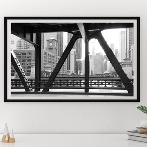 Puede incluir: Fotograf&iacute;a en blanco y negro de un horizonte urbano visto a trav&eacute;s de la estructura de acero de un puente.