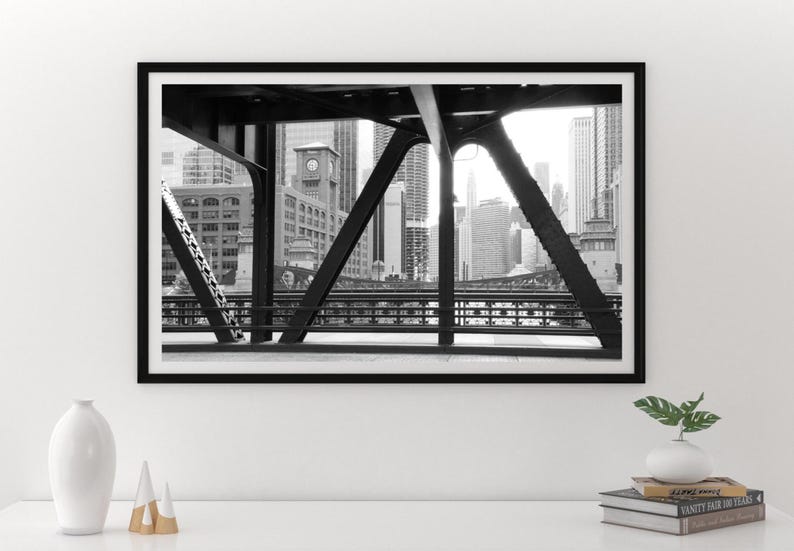 Puede incluir: Fotograf&iacute;a en blanco y negro de un horizonte urbano visto a trav&eacute;s de la estructura de acero de un puente.