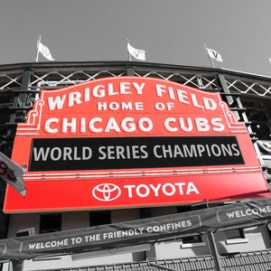 May include: A red and white sign with the words "Wrigley Field, Home of Chicago Cubs, World Series Champions" and the Toyota logo. The sign is attached to a building with a black and white checkered pattern.