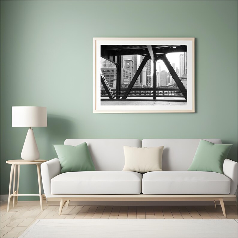 Puede incluir: Fotograf&iacute;a en blanco y negro de un horizonte urbano visto desde debajo de un puente. El puente es de acero y tiene un dise&ntilde;o geom&eacute;trico. Los edificios en el fondo son altos y modernos.