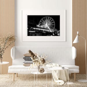 Op de afbeelding: Zwart-witfoto van een reuzenrad 's nachts, met de woorden "Navy Pier" zichtbaar op de steunconstructie van het rad.