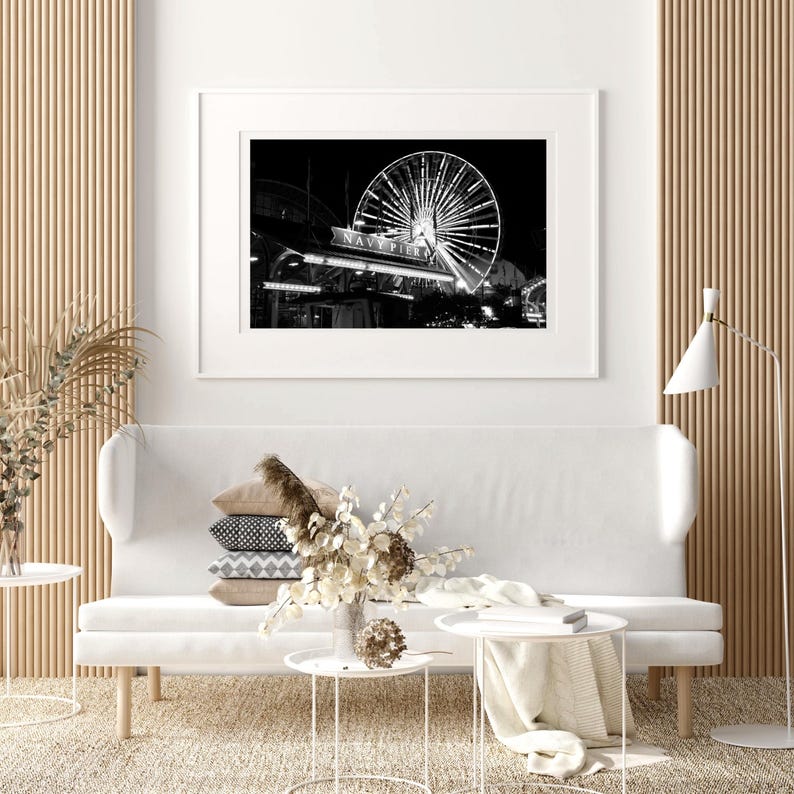 Op de afbeelding: Zwart-witfoto van een reuzenrad 's nachts, met de woorden "Navy Pier" zichtbaar op de steunconstructie van het rad.