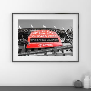 May include: A black and white photograph of Wrigley Field, home of the Chicago Cubs, with a red sign that reads "Wrigley Field, Home of Chicago Cubs, World Series Champions, Toyota".