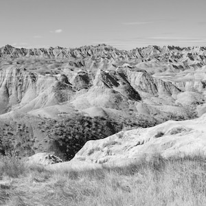 May include: A black and white photograph of a vast, rugged landscape with rolling hills and valleys. The landscape is characterized by its dry, rocky terrain and a distant horizon.