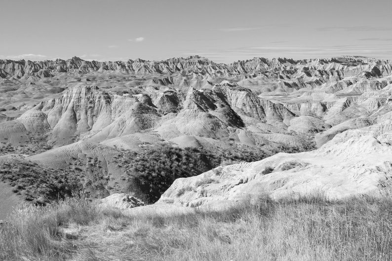 May include: A black and white photograph of a vast, rugged landscape with rolling hills and valleys. The landscape is characterized by its dry, rocky terrain and a distant horizon.