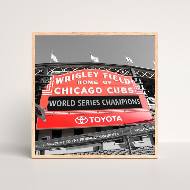 May include: A red and white sign with the text "Wrigley Field, Home of Chicago Cubs, World Series Champions" and a Toyota logo. The sign is at a baseball stadium and has a black and white background.