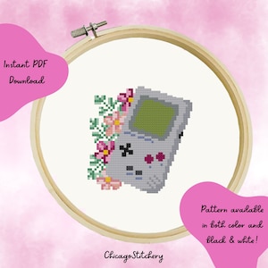 May include: A cross-stitch pattern featuring a gray Game Boy with pink and white flowers. The pattern is available in both color and black and white.