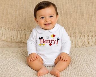 May include: A white long-sleeved baby bodysuit with a Peter Pan collar. The front features the name Henry embroidered in red, surrounded by colorful Mickey Mouse-themed icons including ears, gloves, shoes, and balloons in red, yellow, and black.