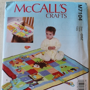 May include: McCall's Crafts sewing pattern M7104 for a baby play mat with colorful animal appliqués. The pattern includes a baby play mat, a high chair toy, and other accessories. The pattern is designed by Susan Cousineau.