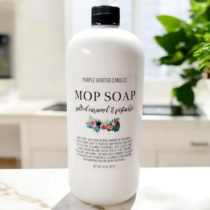 May include: A white plastic bottle of salted caramel and pistachio scented mop soap. The bottle is labeled "Purple Vertigo Candles Mop Soap salted caramel & pistachio" and has a net weight of 32 oz (907 g).