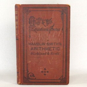 Peut inclure: Un livre vintage brun intitulé "Hamblin Smith's Arithmetic" publié par "Kirkland & Scott". Le livre fait partie de la "Gage & Co's Educational Series".
