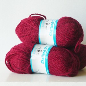 May include: Three balls of deep red yarn, each with a label that reads "Shetland Style Chunky" in white text on a blue background.
