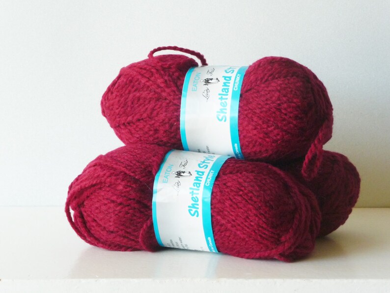 May include: Three balls of deep red yarn, each with a label that reads "Shetland Style Chunky" in white text on a blue background.