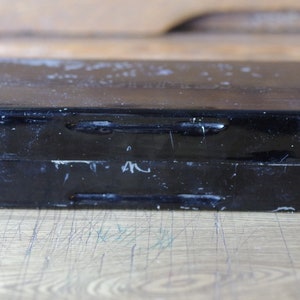 Pu&ograve; includere: Una scatola di metallo nera con un coperchio incernierato. La scatola ha due chiusure metalliche sul davanti e una finitura usurata e sbiadita.