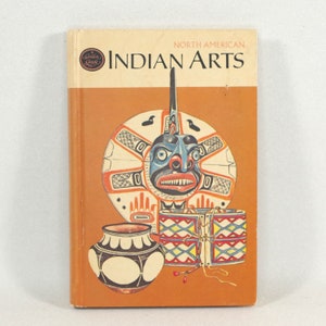 Puede incluir: Un libro antiguo titulado "North American Indian Arts" con una cubierta de color amarillo dorado. La portada presenta ilustraciones de arte nativo americano, incluyendo una máscara, tambores y cerámica, sobre un fondo naranja. El libro tiene el logo "Golden Guide".