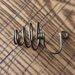 Pu&ograve; includere: Un filo metallico avvolto a spirale con un gancio all'estremit&agrave;. Il filo &egrave; di colore marrone chiaro ed &egrave; avvolto a spirale.