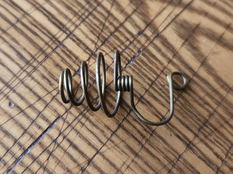 Pu&ograve; includere: Un filo metallico avvolto a spirale con un gancio all'estremit&agrave;. Il filo &egrave; di colore marrone chiaro ed &egrave; avvolto a spirale.