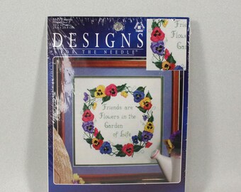 May include: Cross stitch pattern featuring a wreath of colorful flowers with the text "Friends are Flowers in the Garden of Life". The pattern is on a white background with a light blue border. The pattern is from the Designs for the Needle brand.