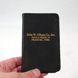 May include: A black leather-bound notebook with gold lettering that reads "John W. Fillman Co., Inc. 1020-22-24 Filbert St. Philadelphia, Penna."