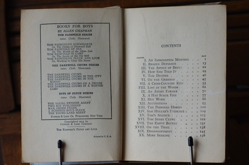 May include: A book cover with the title "Books for Boys" by Allen Chapman. The book features a list of titles in the "Tom Fairfield" and "Darewell Chums" series, as well as the "Boys of Pluck" series. The book also includes a table of contents with chapter titles and page numbers.