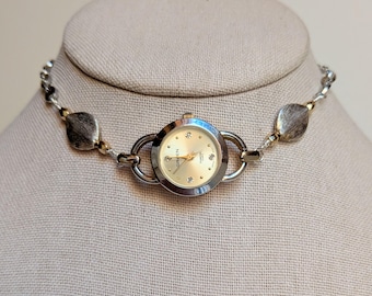 Collar gargantilla vintage Gruen con diseño de reloj, color plata con detalles dorados y cuentas.