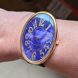 May include: A gold-toned oval wristwatch with a blue marbled face and gold numerals. The watch face reads "PIERRE QUARTZ" and has a black leather band. The watch is marked "JAPAN MOVT".