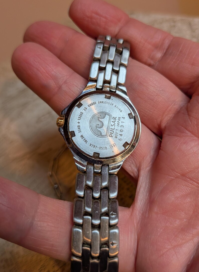 May include: A silver-toned Pulsar watch with a metal band. The watch face is visible, displaying the brand name and model information. The back of the watch reads "Water Resistant 10BAR ST. STEEL + BASE METAL V782-0510".