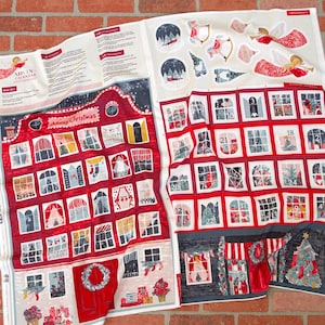 May include: A fabric advent calendar panel featuring a red and white house design with numbered windows, Christmas tree, and gift illustrations. The top section includes printed instructions and cut-out ornament graphics with angels and snow globes.