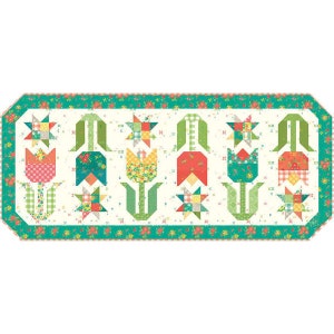 May include: A white table runner with a green border and a floral design. The design features a row of tulips with green stems and leaves, red, yellow, and blue petals, and a star-shaped design at the base of each tulip.