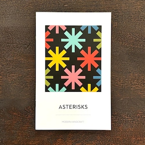 May include: A white booklet with a black background and a colorful geometric pattern of stars. The title of the booklet is "ASTERISKS" and the subtitle is "MODERN HANDICRAFTS".