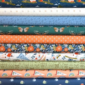 May include: A stack of various patterned fabric rolls. Designs include camping scenes, butterflies, floral patterns, and text that reads "WILD LIFE" and "GET LOST". Colors include blue, orange, green, and white.
