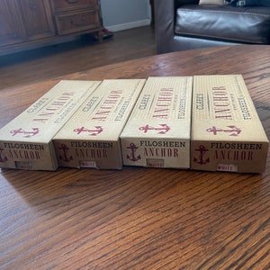 May include: Four brown cardboard boxes with white text and a red anchor logo. The boxes are labeled "Clarks Anchor" and "Filosheen Anchor".