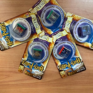 May include: Six Harry Potter collectible dice game booster packs. Each pack features a different character and a small plastic dice container with a character inside. The packs are gold and black with the Harry Potter logo.