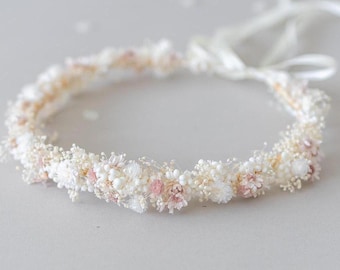 May include: A delicate white and pink floral crown with a white ribbon tie. The crown is made of dried flowers and is perfect for a wedding or special occasion.