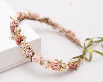 May include: A delicate floral crown with pink and white dried flowers, tied with a green ribbon.