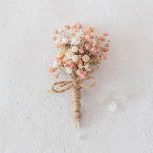 Boutonniere for the groom with dried flowers in cream and dusky pink. Buttonhole with preserved flowers for groomsman with baby&#39;s breath