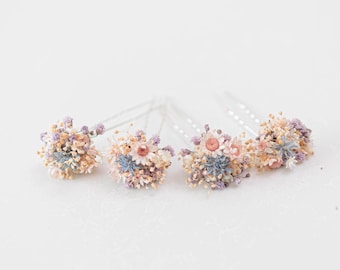 Puede incluir: Conjunto de cuatro horquillas para el pelo florales con delicadas flores secas en tonos rosa, azul y blanco. Las flores están dispuestas en un racimo y sujetas a una horquilla de plata.