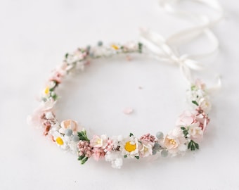May include: A delicate floral crown made with white and pink flowers, accented with small green leaves and a white ribbon.