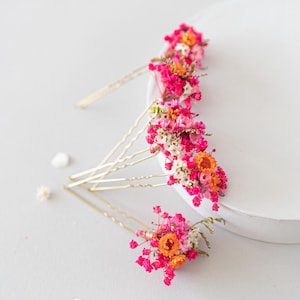 Handgefertigte Haarnadeln mit konservierten Blumen, darunter zarte Gänseblümchen und Schleierkraut in Orange, rosa und pink. Diese romantischen Haarblumen in warmen Herbstfarben sind ein vielseitiger Haarschmuck für Boho-Styles und natürliche Looks. Perfekt als bunter Haarschmuck mit Wildblumen und Schleierkraut für Sommerfeste, Oktoberfest, Hochzeiten, Weihnachten, Brautpartys, Geburtstage, Babypartys. Ideal als herbstliche Accessoires, Haarklammern.