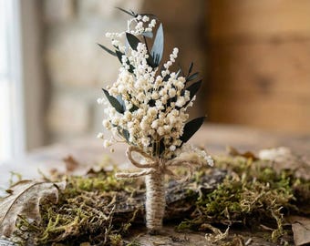 Boutonniere for the groom with babys breath and eucalyptus. Bohemian buttonhole with preserved flowers for groomsman in white and green