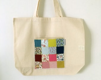 Large tote bag adorned with a patchwork pocket