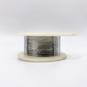 May include: A spool of silver wire on a white plastic base.